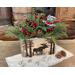 This shows a handmade wooded box that has a moose and pine trees wood-burned on the front. The box hold a Christmas greenery arrangment. 